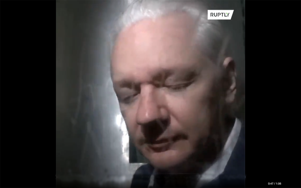 Julian Assange den 21 okt 2019 i London efter ett förhör om utlämning till USA. Assange är bländad av fotografens videolampa. Foto: Ruplty.com via Twitter